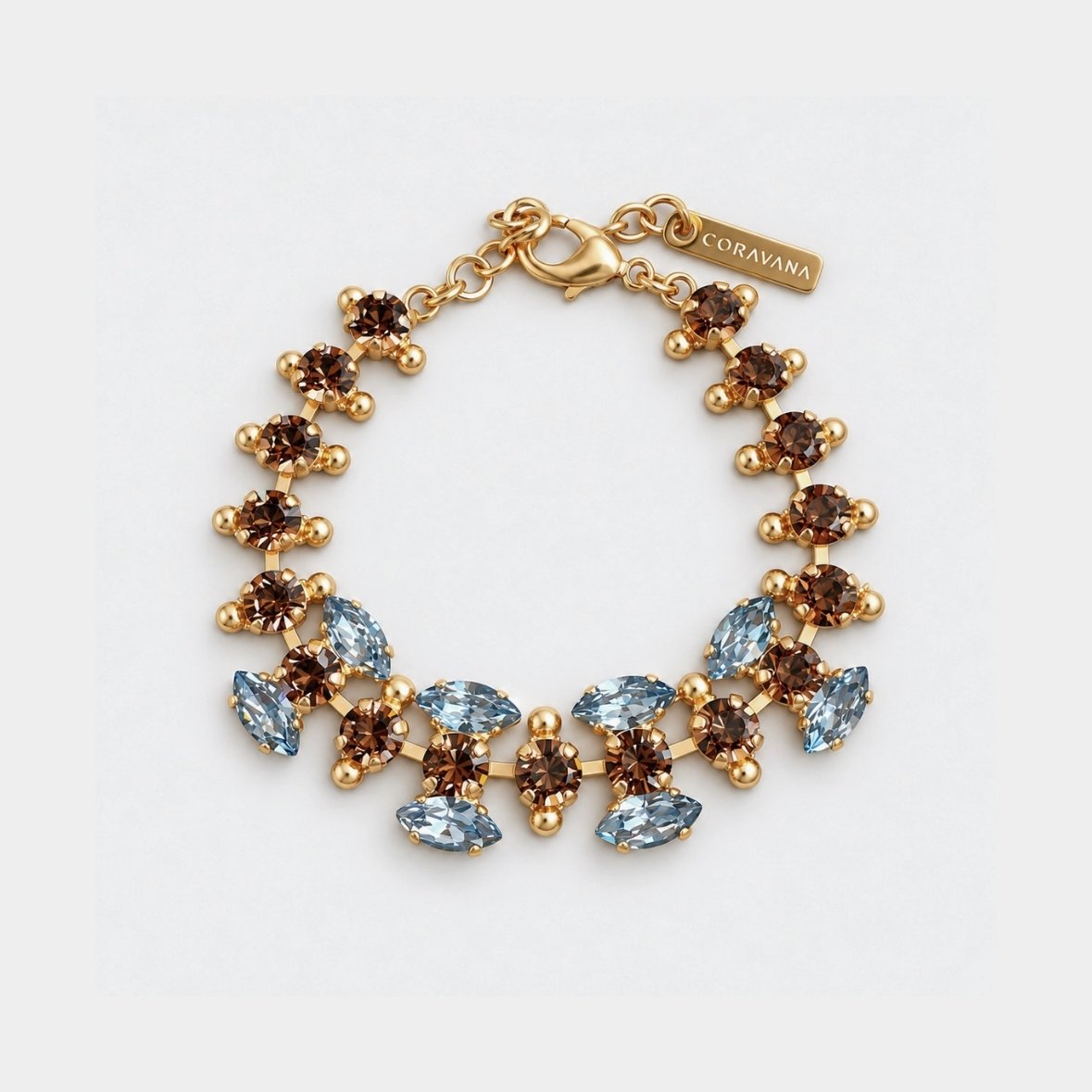 A gold-plated statement bracelet by Koravna, featuring alternating round brown smoky quartz and marquise-cut light blue aquamarine crystals, displayed on a clean white background.