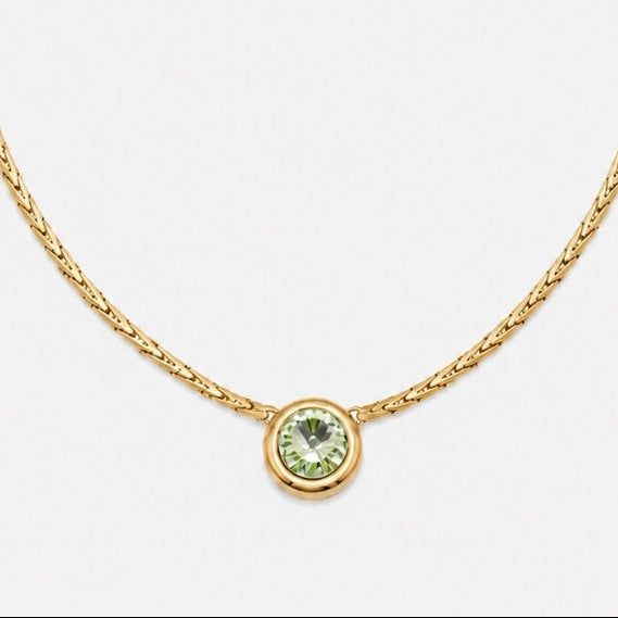 A gold chain necklace with a small round bezel-set green gemstone pendant, displayed on a clean white background.