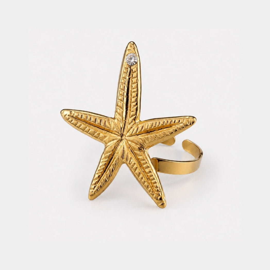 Gold starfish-shaped ring on a white background