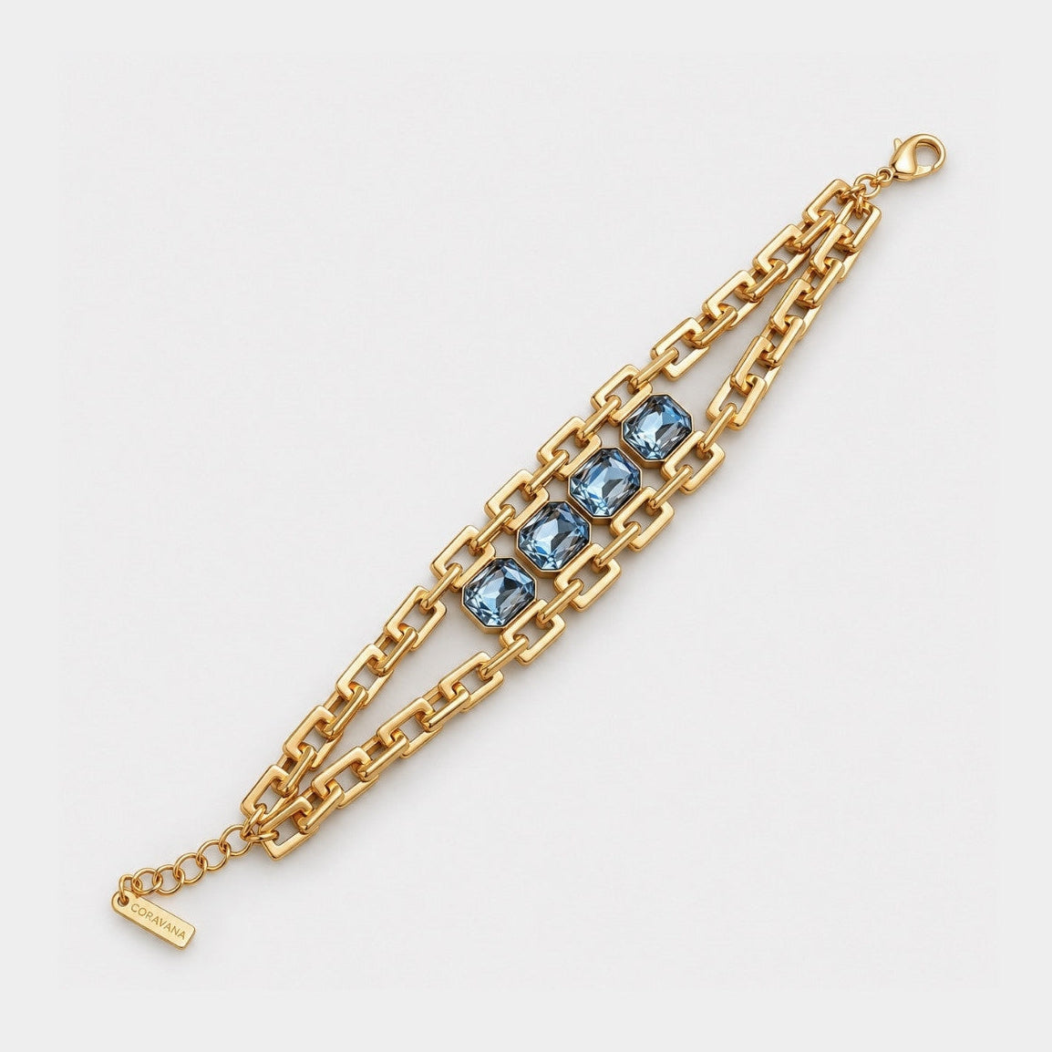 A gold chain bracelet featuring three rectangular blue gemstones in the center, displayed on a clean white background.