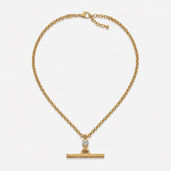 A gold chain necklace with a horizontal bar pendant and a small clear gemstone accent, displayed on a light gray background.