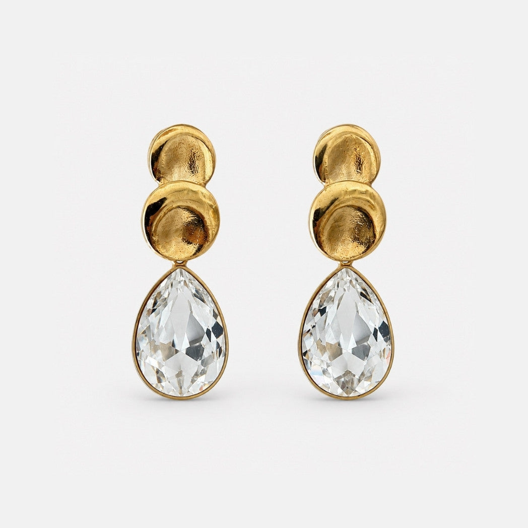 Gold earrings with teardrop-shaped clear gemstones on a white background