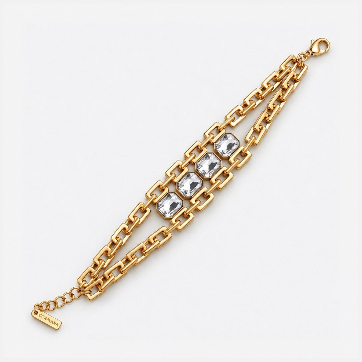 A gold chain bracelet featuring three square-cut clear crystals set in a rectangular gold frame, with a lobster clasp and extender chain on a light gray background.