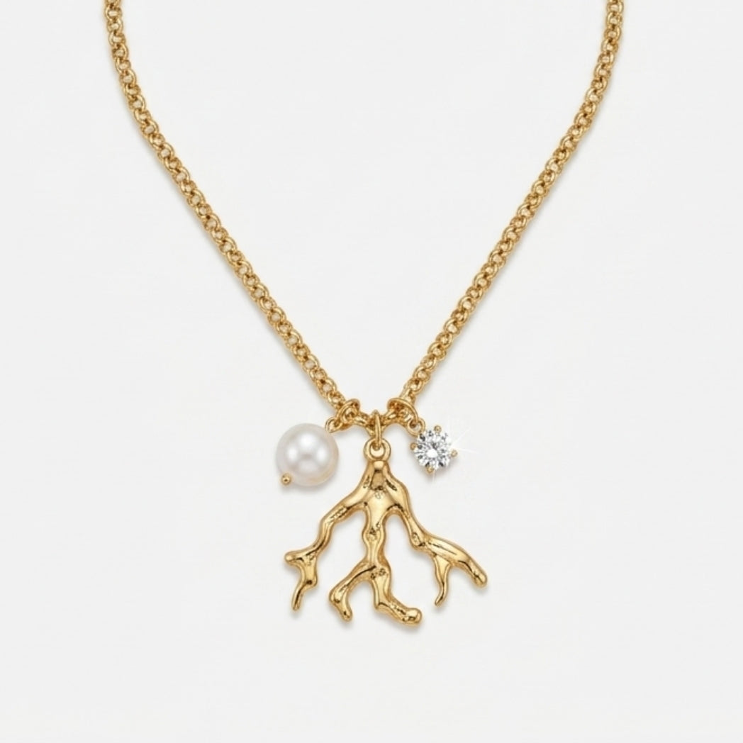 Gold necklace with a pearl and branch charm on a white background