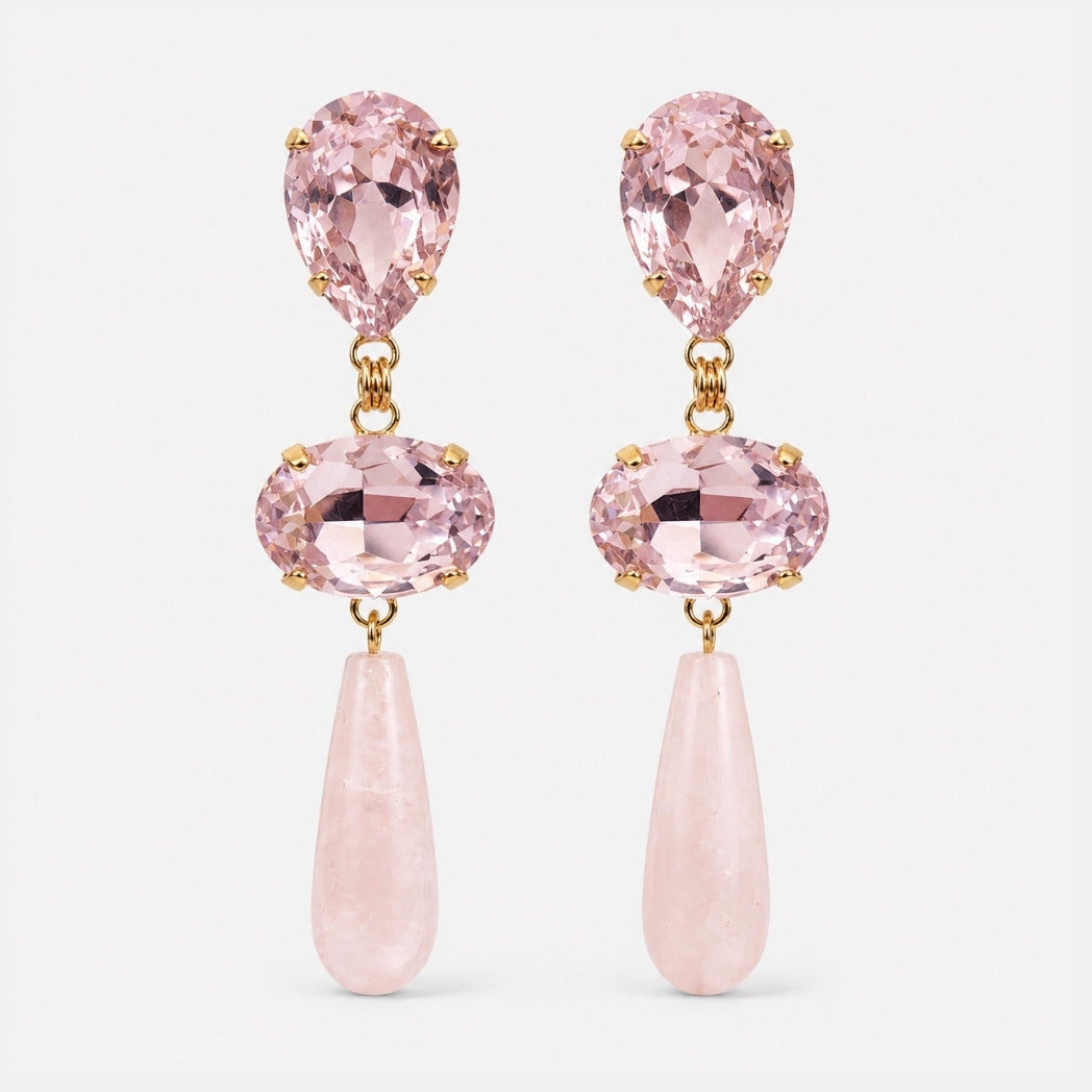 A pair of gold-tone drop earrings featuring a teardrop-shaped pink gemstone, an oval pink gemstone, and a larger teardrop-shaped pale pink stone below, set against a light gray background.