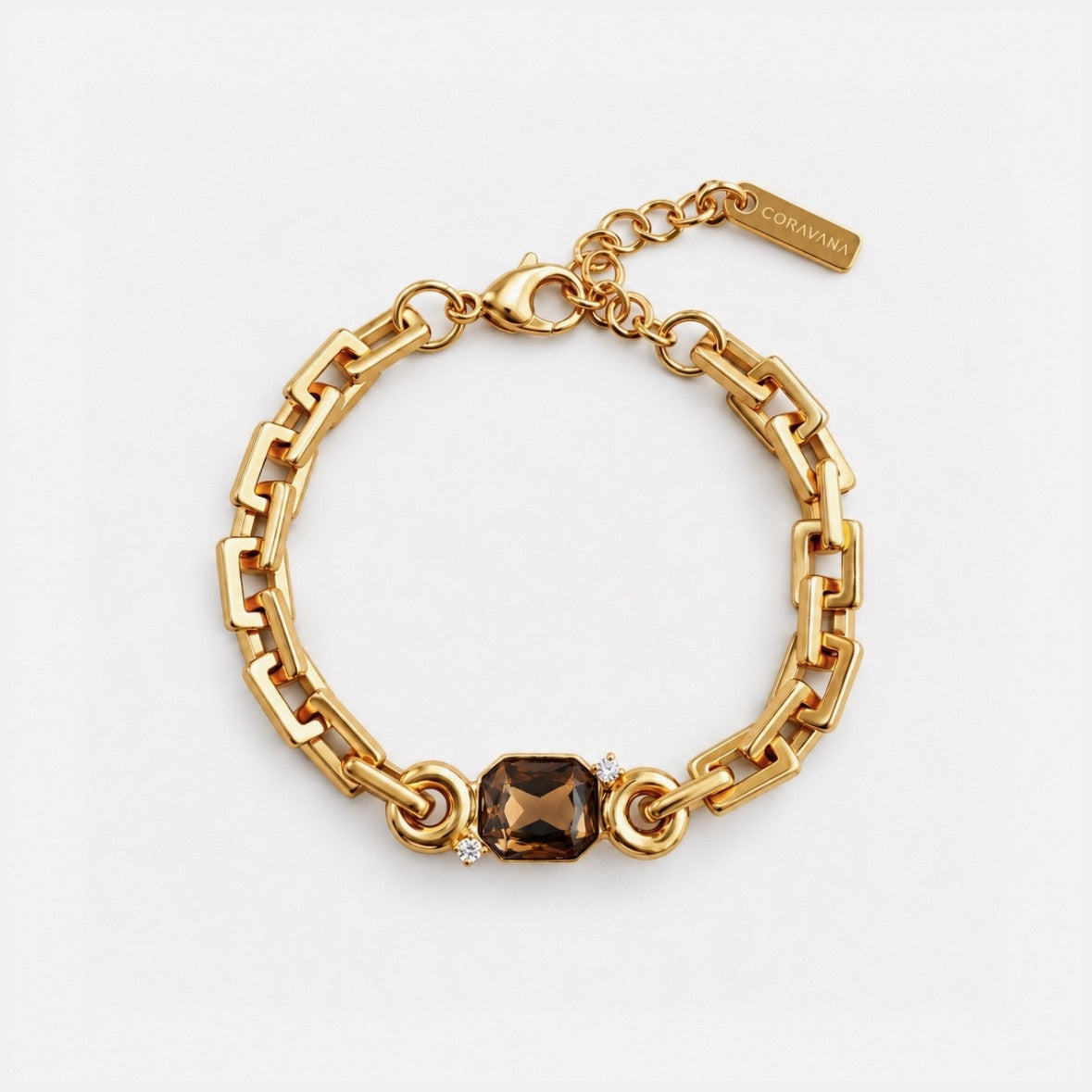 A gold-toned chain bracelet with a central faceted smoky brown gemstone and a small clear accent stone, photographed on a clean white background. A small tag is attached near the clasp.