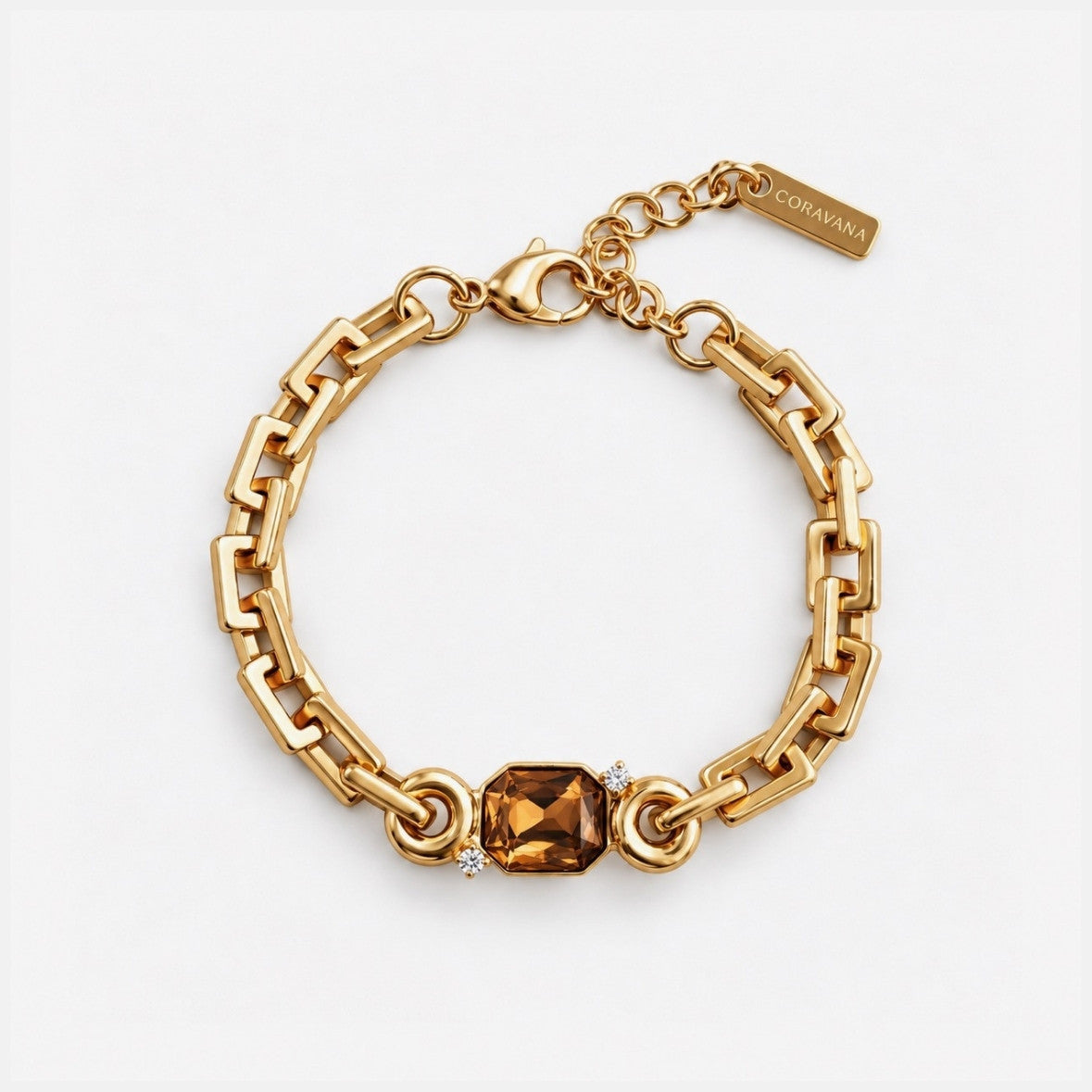 A gold-tone chain bracelet with a central rectangular faceted amber gemstone and small clear accent stones, photographed on a clean white background. A small tag is attached near the clasp and reads COCOANA.