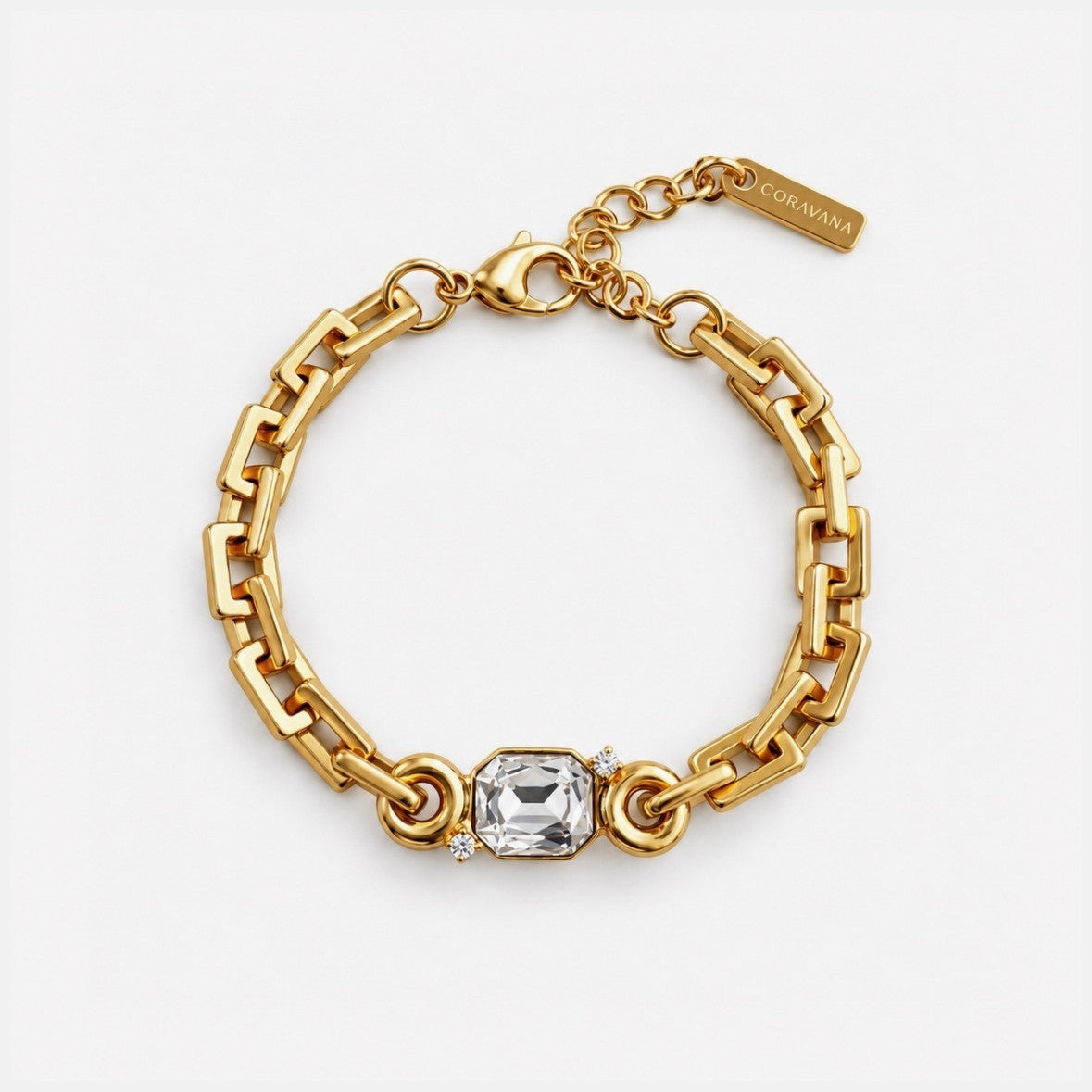 A gold chain bracelet with a central clear rectangular gemstone and small side stones, photographed on a clean white background. A small tag is attached near the clasp and appears to read CORDANA.