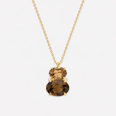 A gold chain necklace with a double-stone pendant featuring a large oval brown smoky gemstone and a smaller round faceted brown gemstone, set against a light gray background.