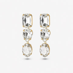 A pair of gold drop earrings featuring three clear faceted gemstones in rectangular, pear-shaped, and oval cuts, set against a light gray background.