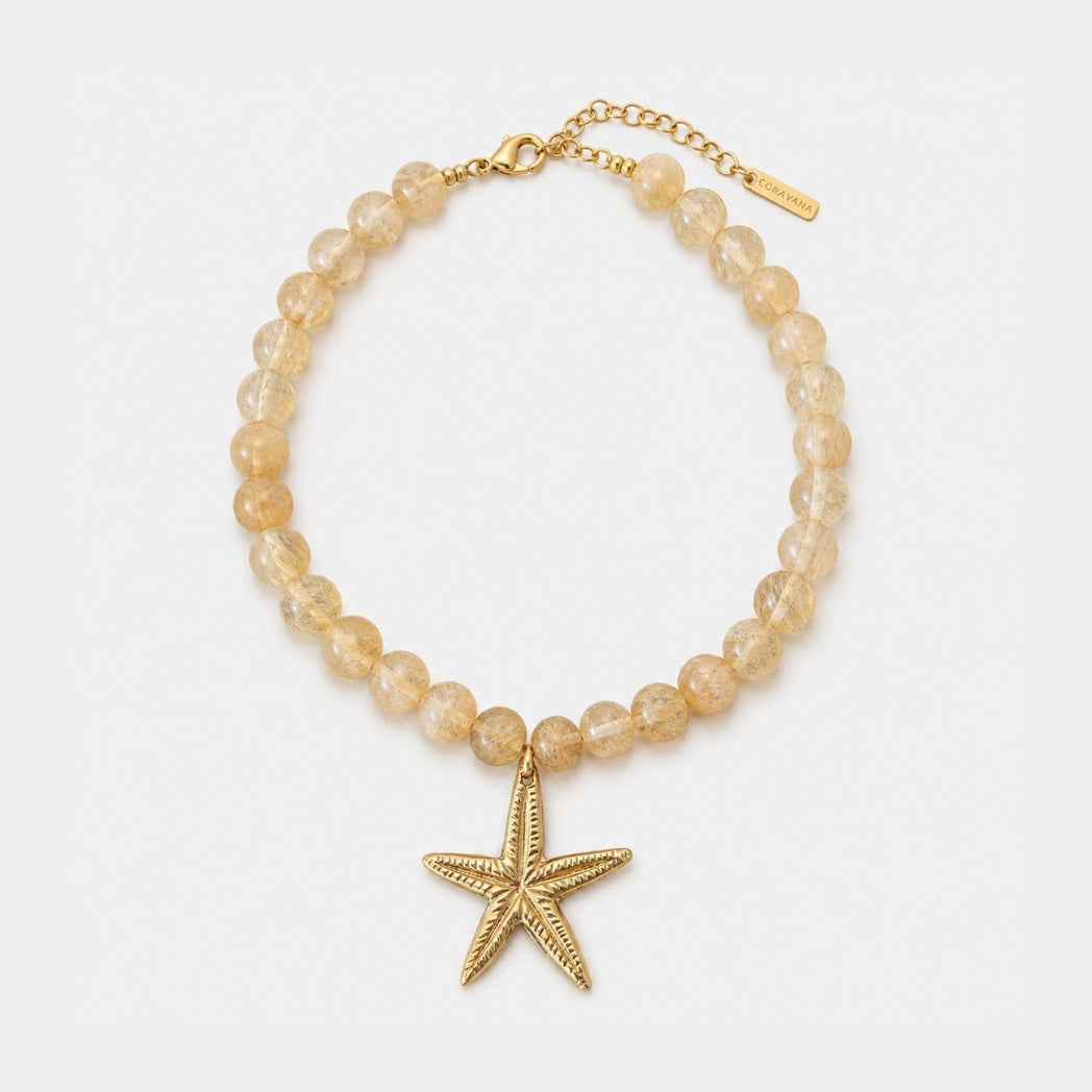 Beaded bracelet with a gold starfish charm on a white background
