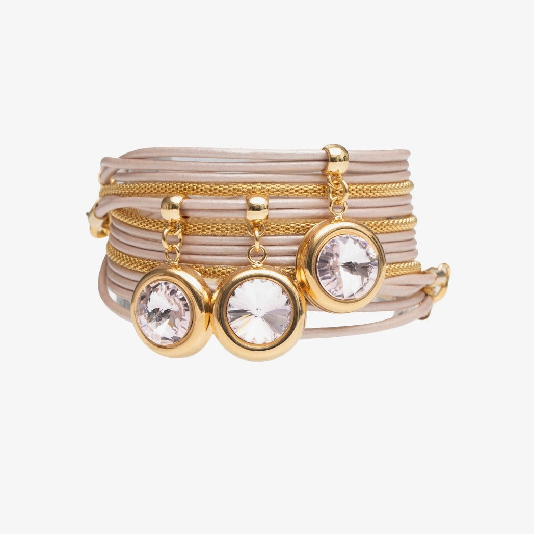 Set of gold and beige bracelets with crystal charms on a white background