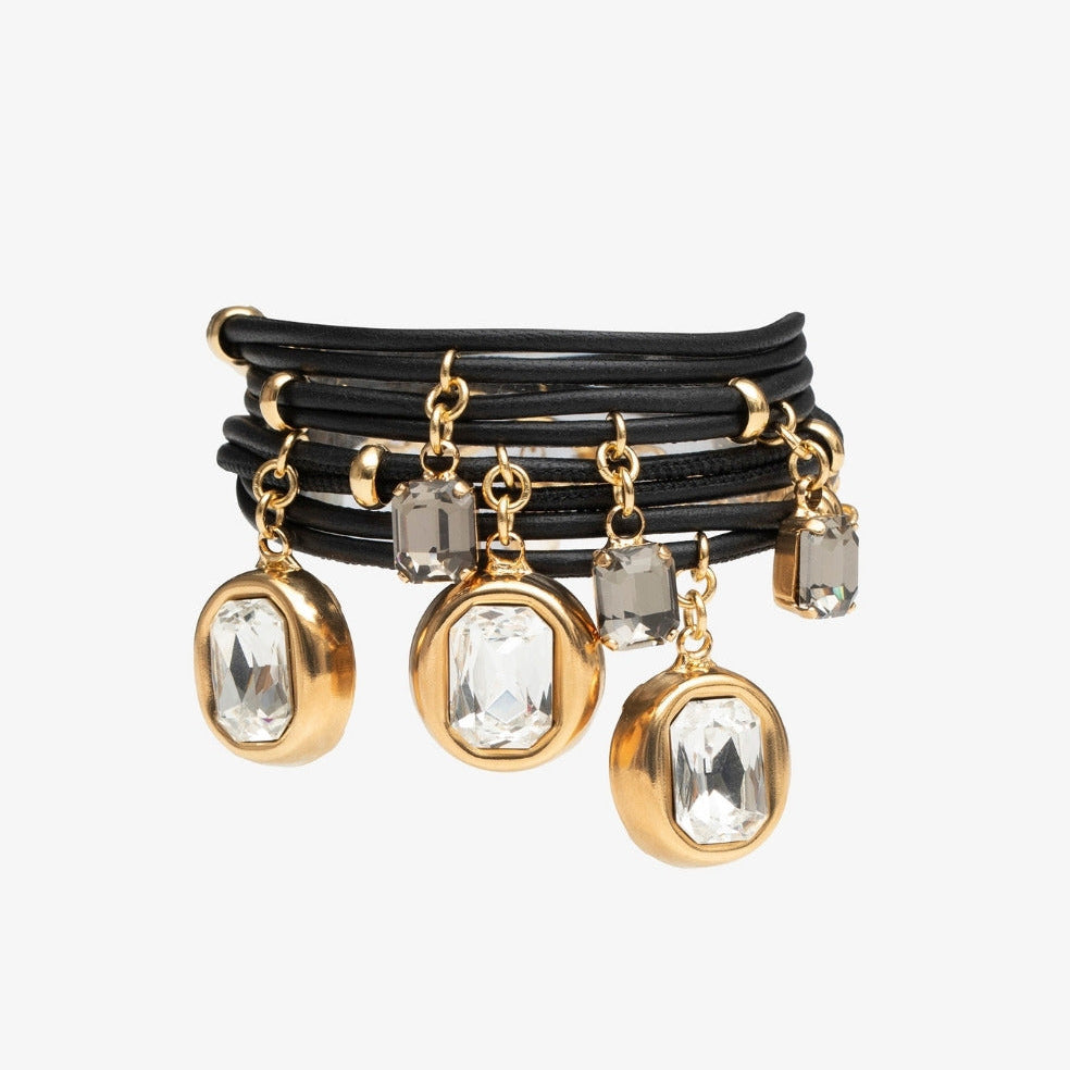 Set of black leather bracelets with gold and crystal charms on a white background