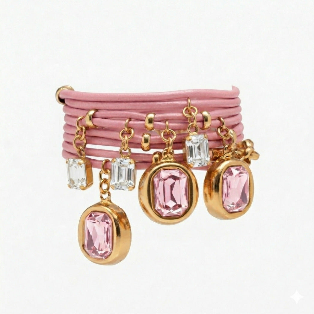 Set of pink bracelets with gold and clear gemstone charms on a white background