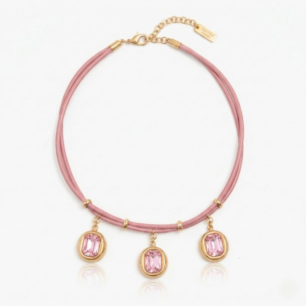 Pink necklace with gold accents and pink gemstones on a white background