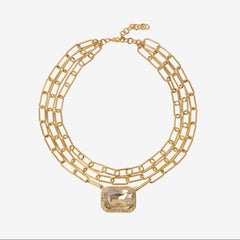 Gold chain necklace with a central gemstone on a white background