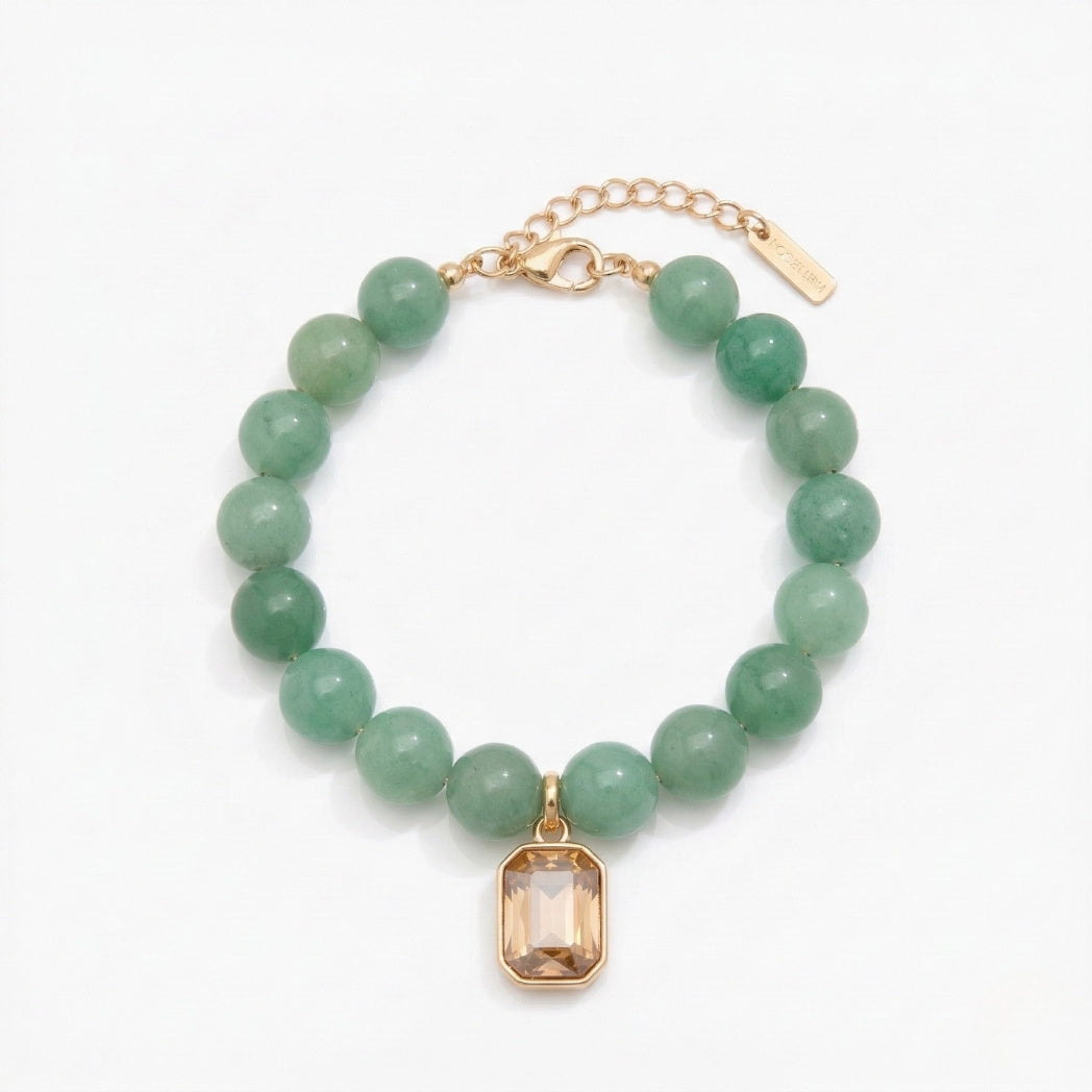 Green beaded bracelet with a gold charm on a white background