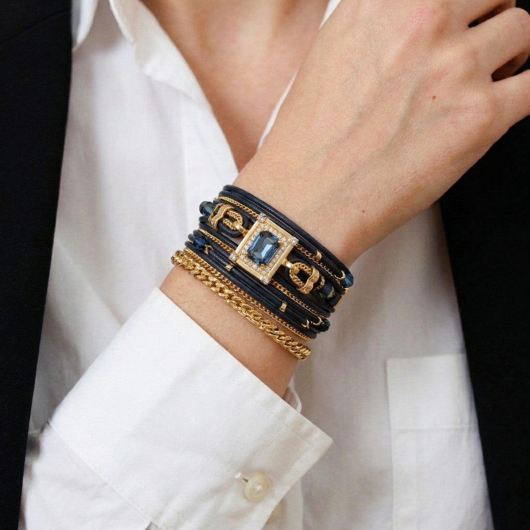 Close-up of a wrist wearing multiple bracelets with a white shirt and black jacket.