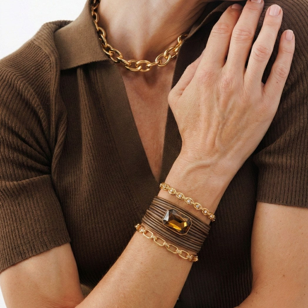 Close-up of a person wearing gold chain jewelry on a brown background