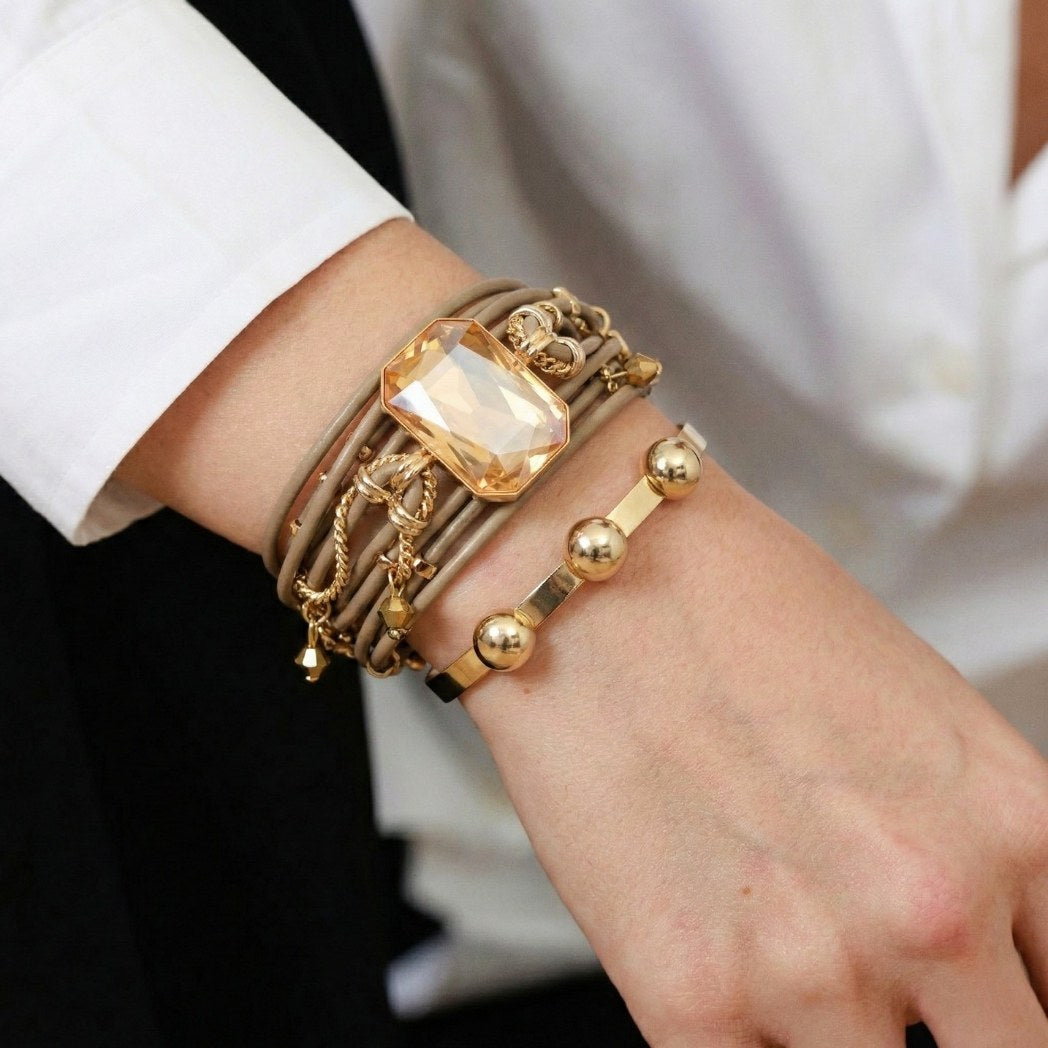 Close-up of a wrist wearing multiple gold bracelets with a neutral background