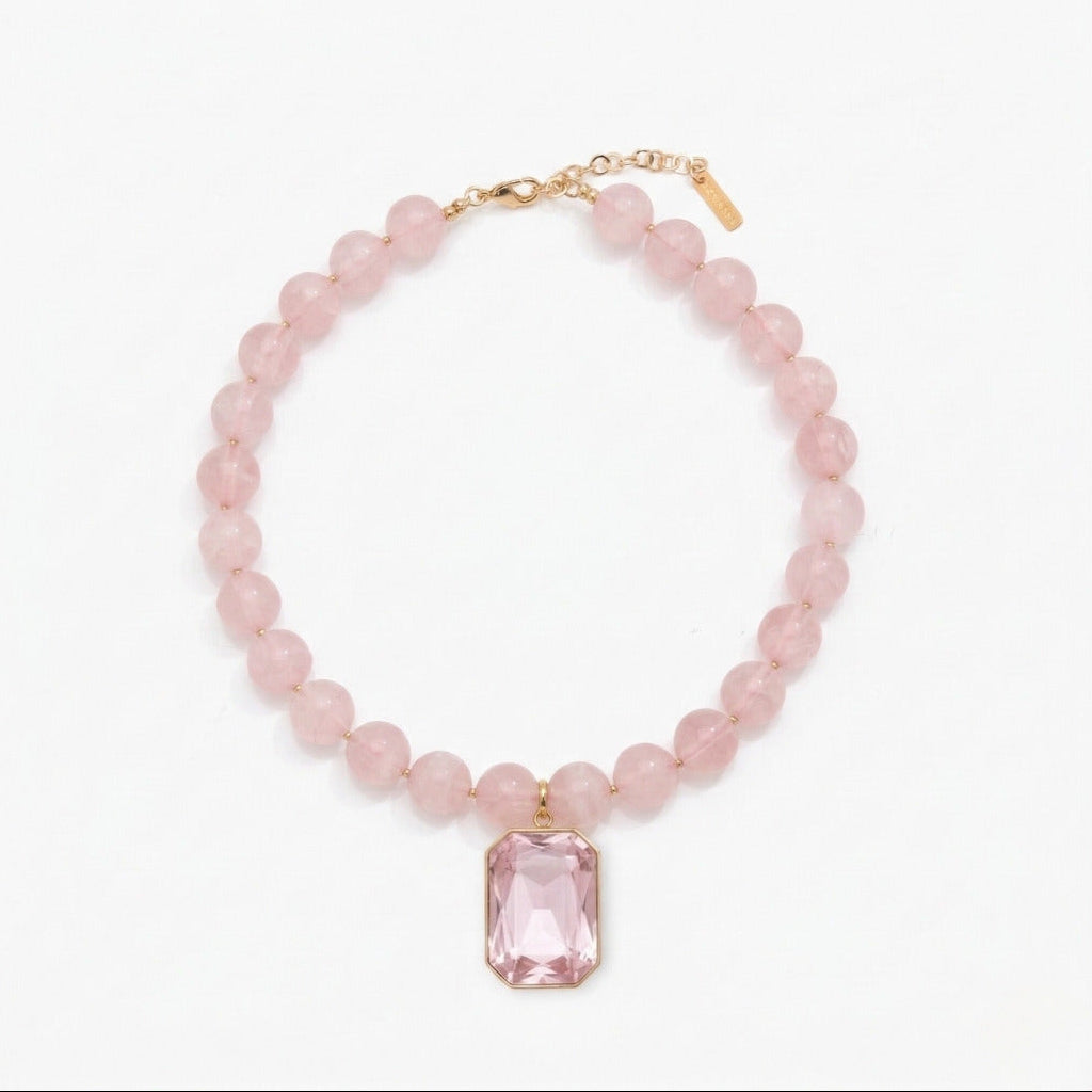 Pink beaded necklace with a rectangular pink gemstone pendant on a white background