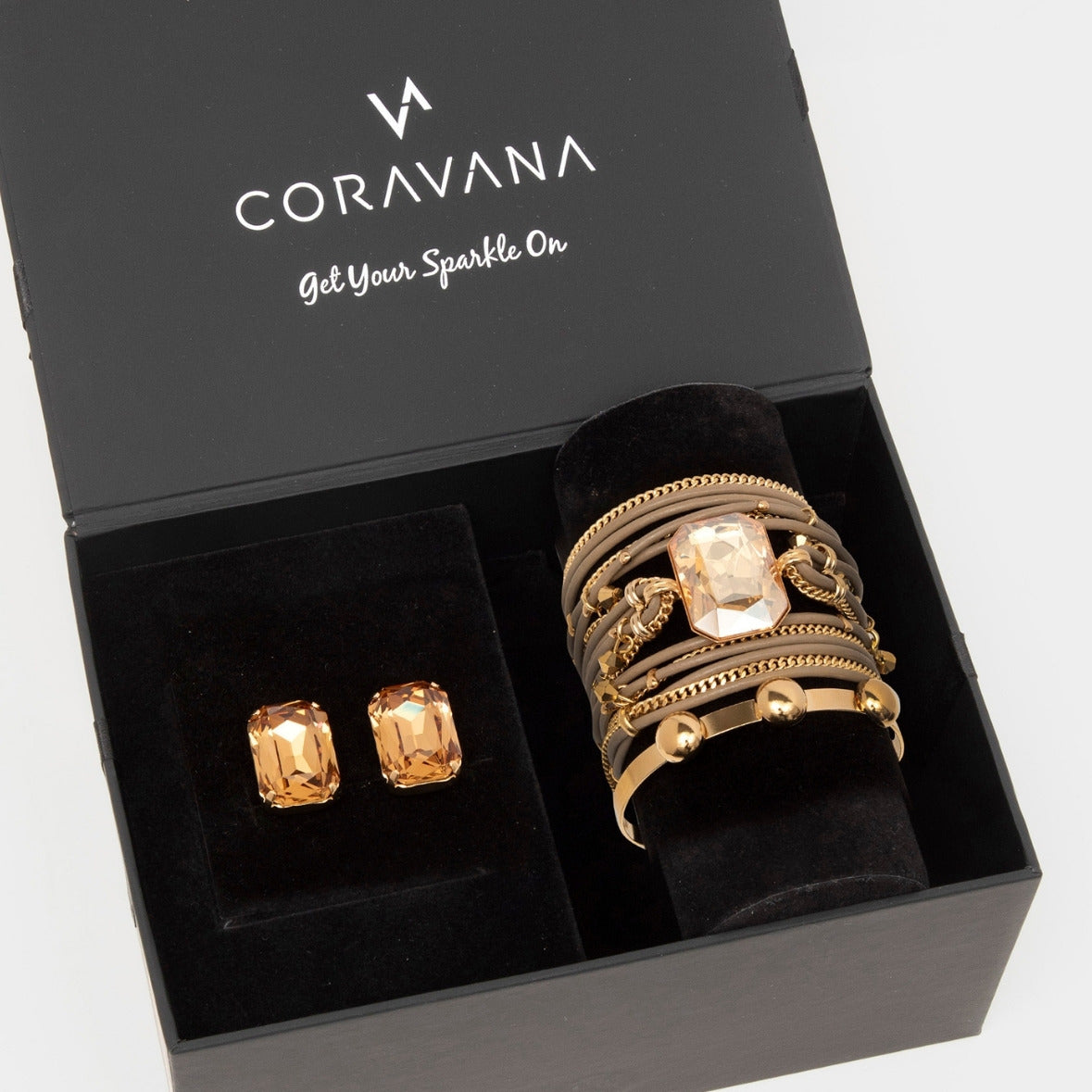 Gold jewelry set including rings and earrings in a Coravana box.