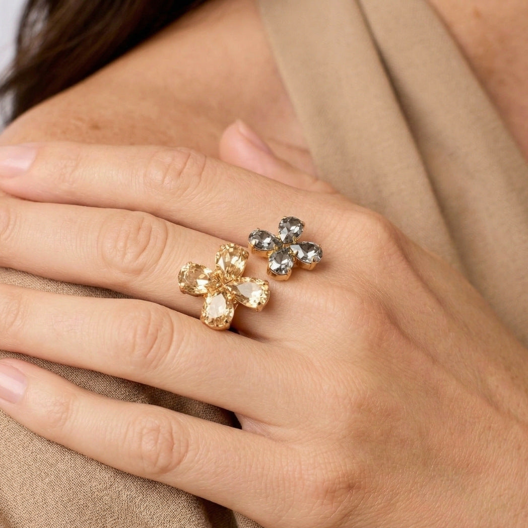 Close-up of a hand wearing two floral-patterned rings with gold and silver stones.