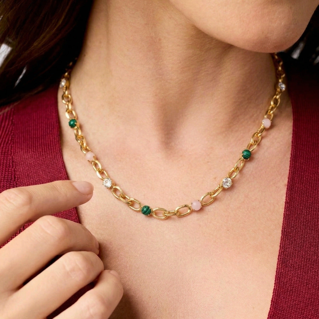 Gold chain necklace with colored beads worn by a person