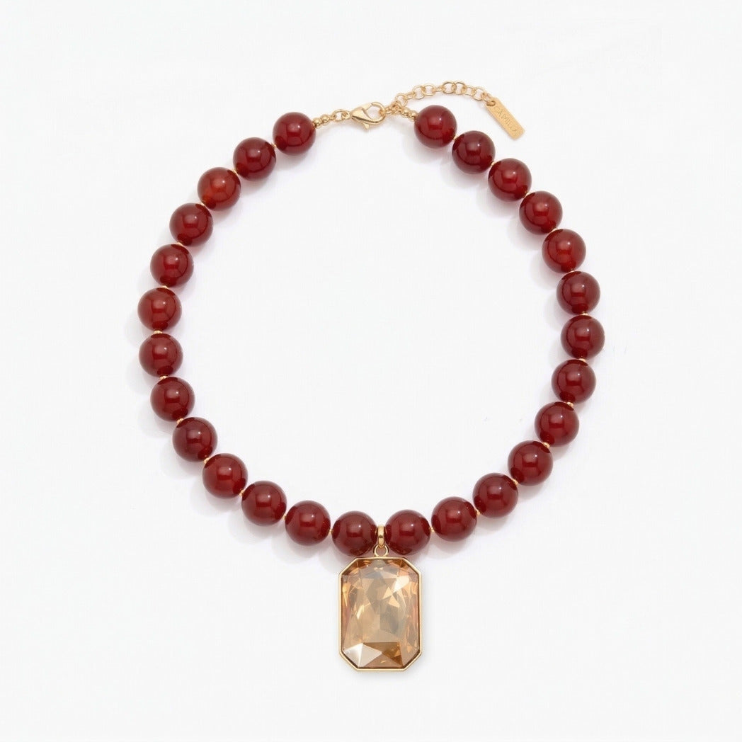 Necklace with red beads and a gold pendant on a white background