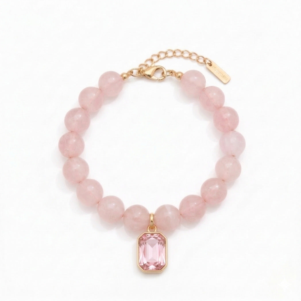 Pink beaded bracelet with a pink pendant on a white background
