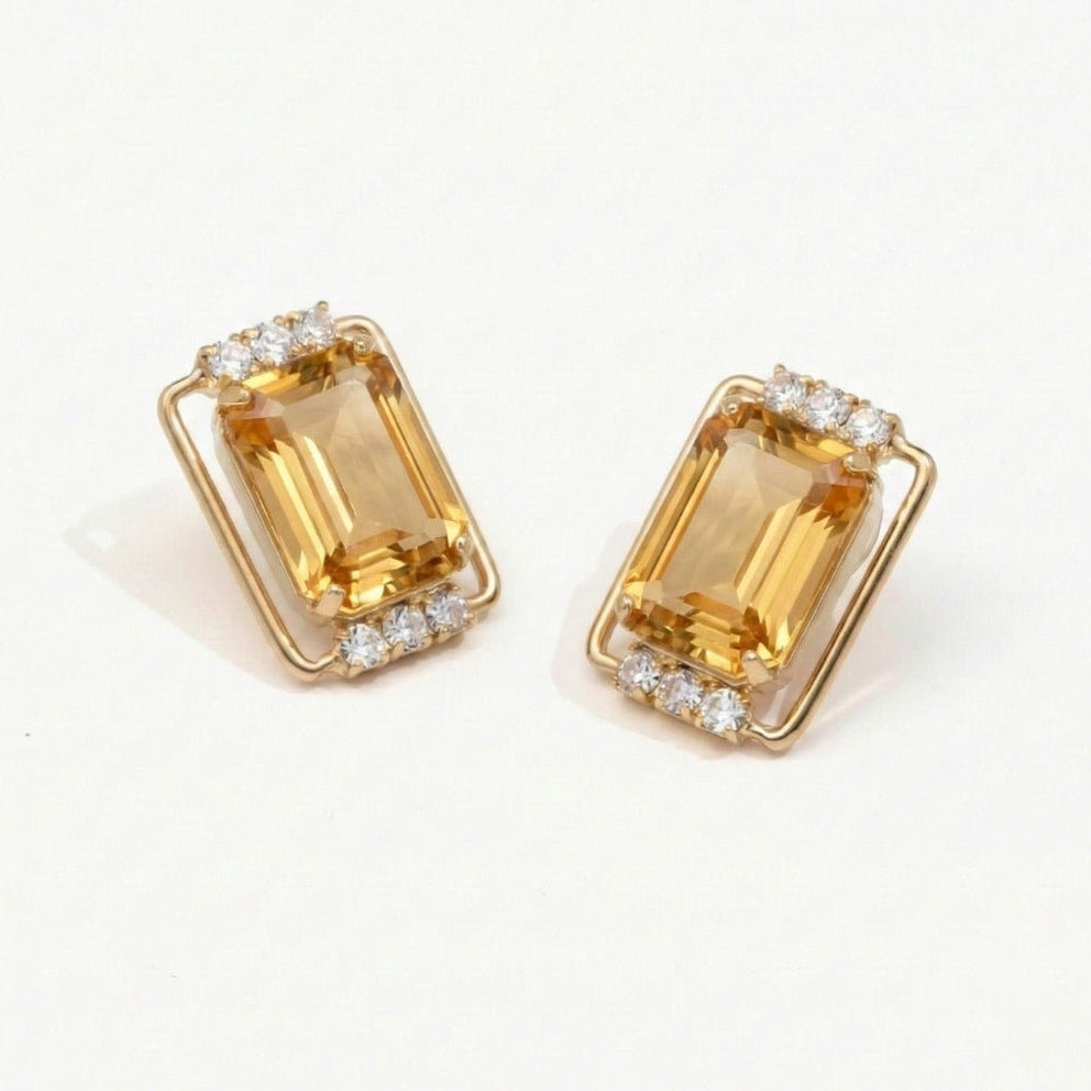 Gold earrings with rectangular gemstones on a light background