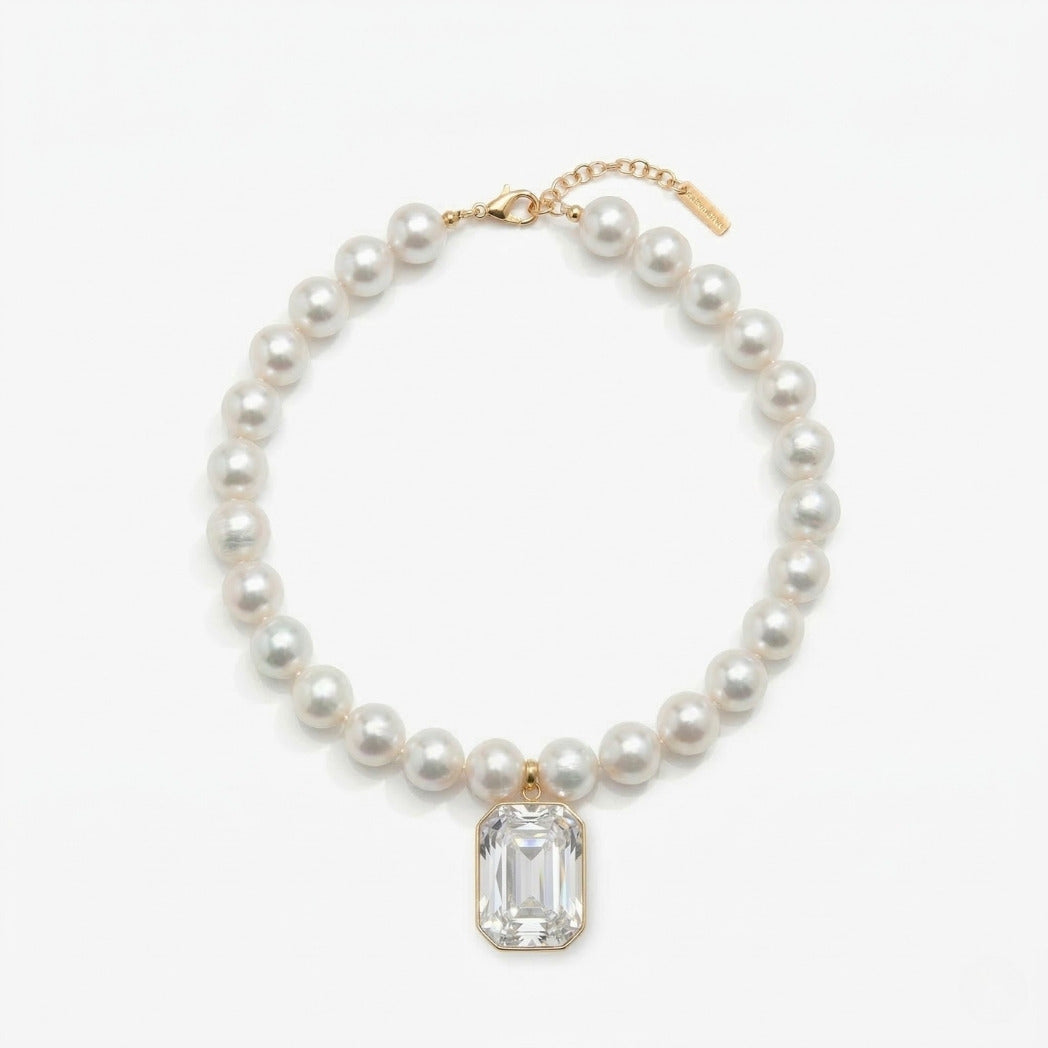 Pearl necklace with a clear gemstone pendant on a white background