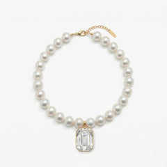Pearl necklace with a clear gemstone pendant on a white background