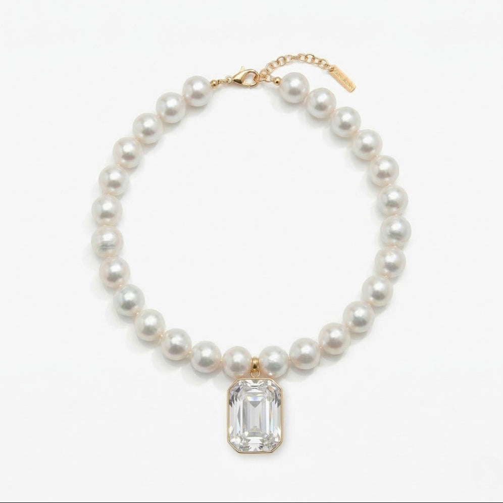 Pearl necklace with a clear gemstone pendant on a white background