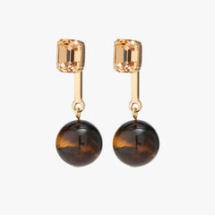 Pair of earrings with gold top and brown round bottom on a white background
