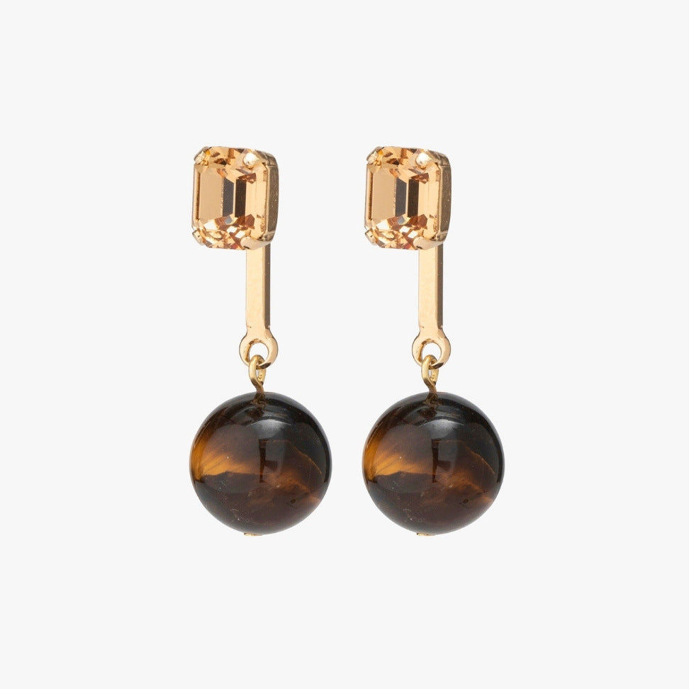 Pair of earrings with gold top and brown round bottom on a white background