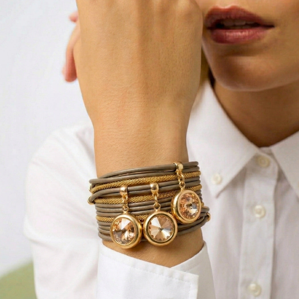 Close-up of a person wearing multiple bracelets with gold accents on a white background