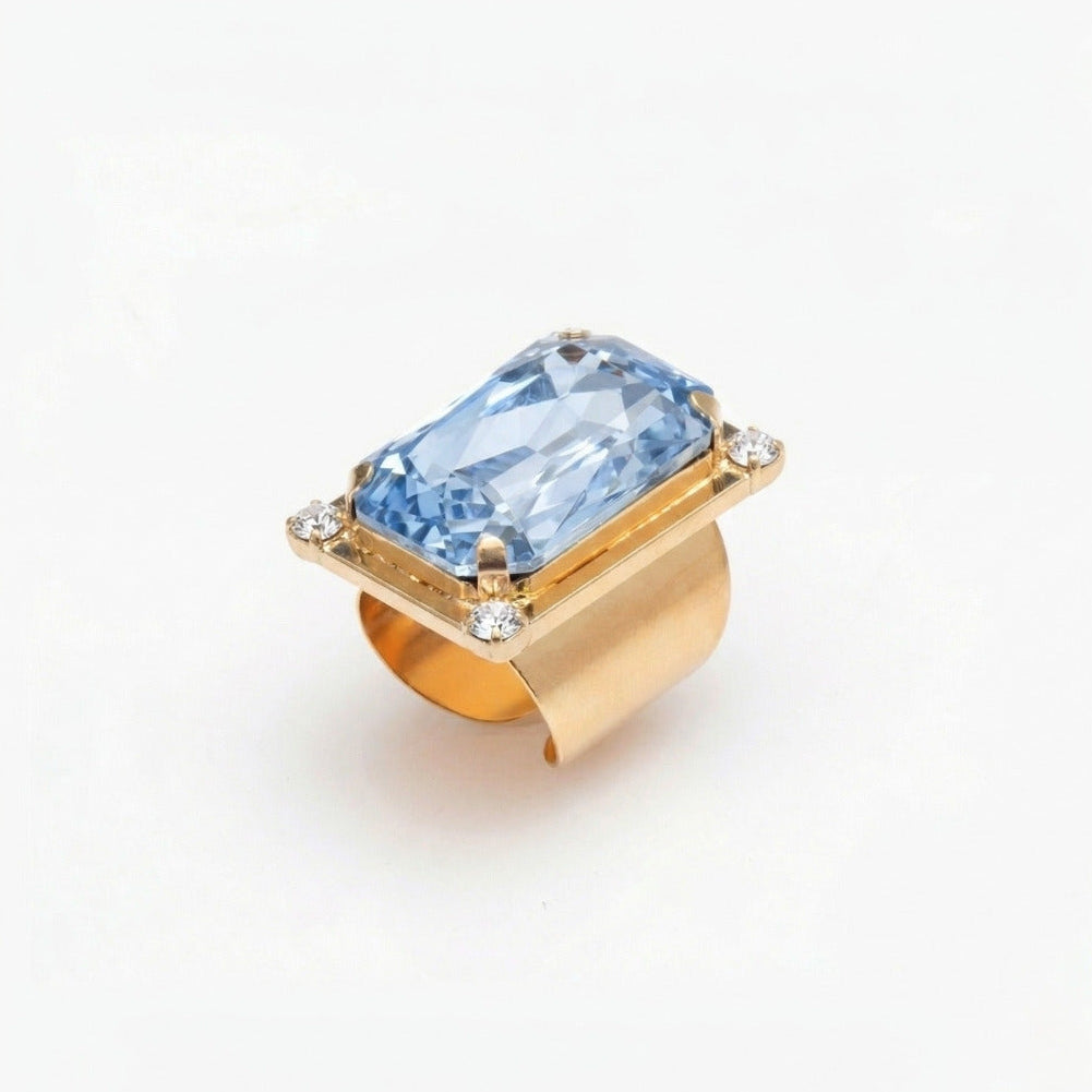 Gold ring with a blue gemstone on a white background