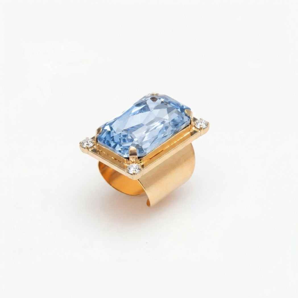 Gold ring with a blue gemstone on a white background