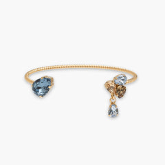 Gold bracelet with blue, brown, and clear gemstones on a white background