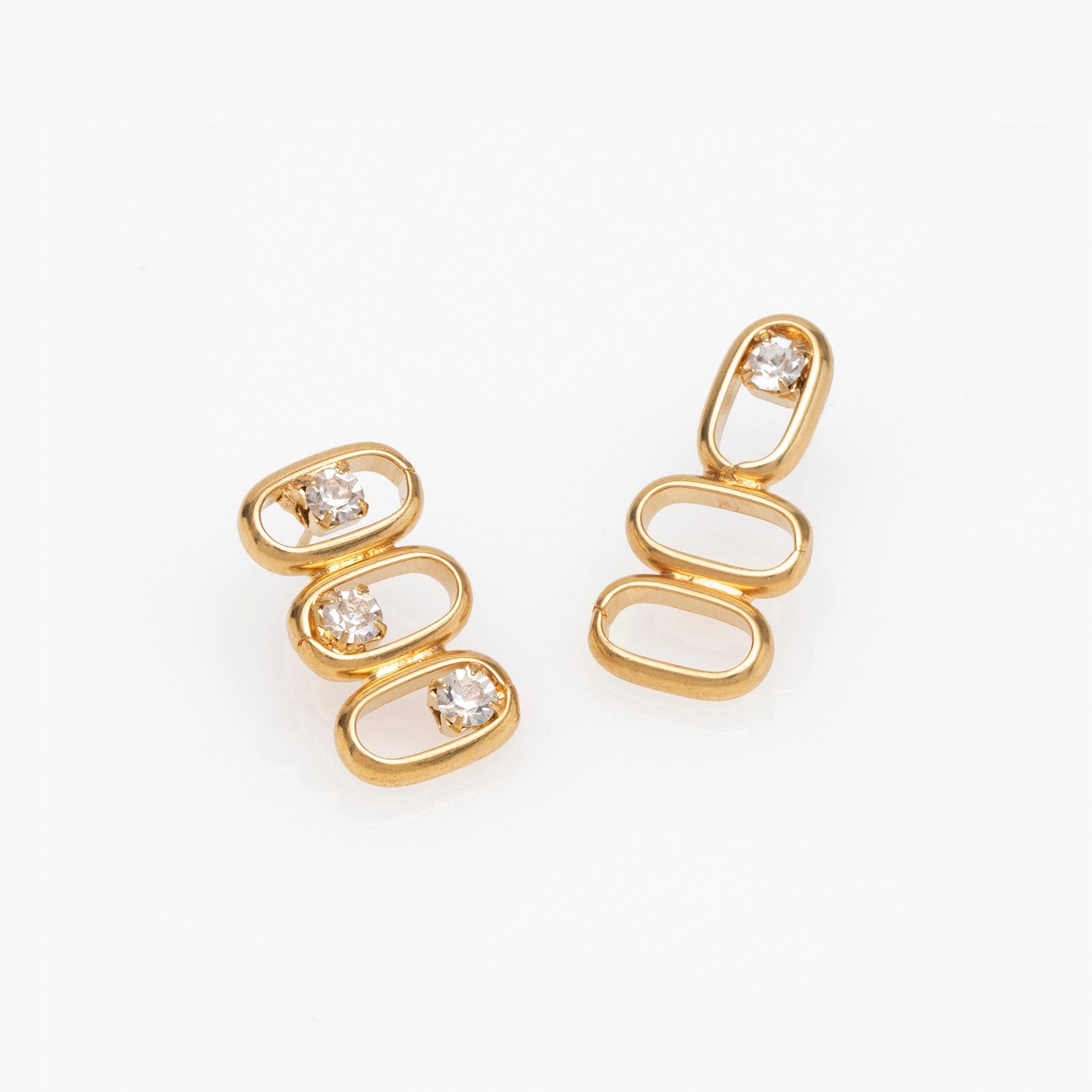 Gold earrings with diamond-like stones on a white background