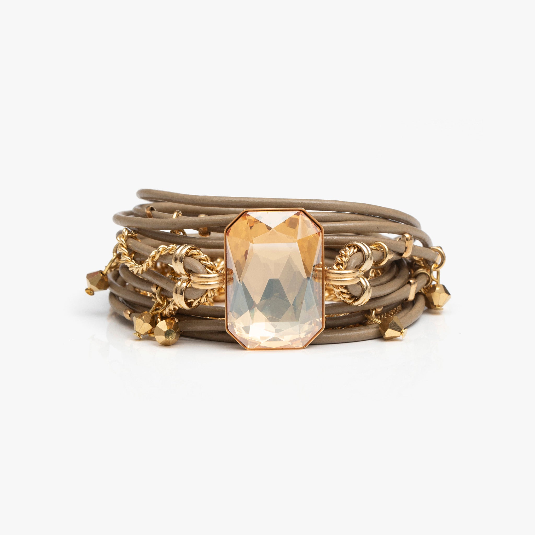 Stack of gold bracelets with a prominent crystal on a white background