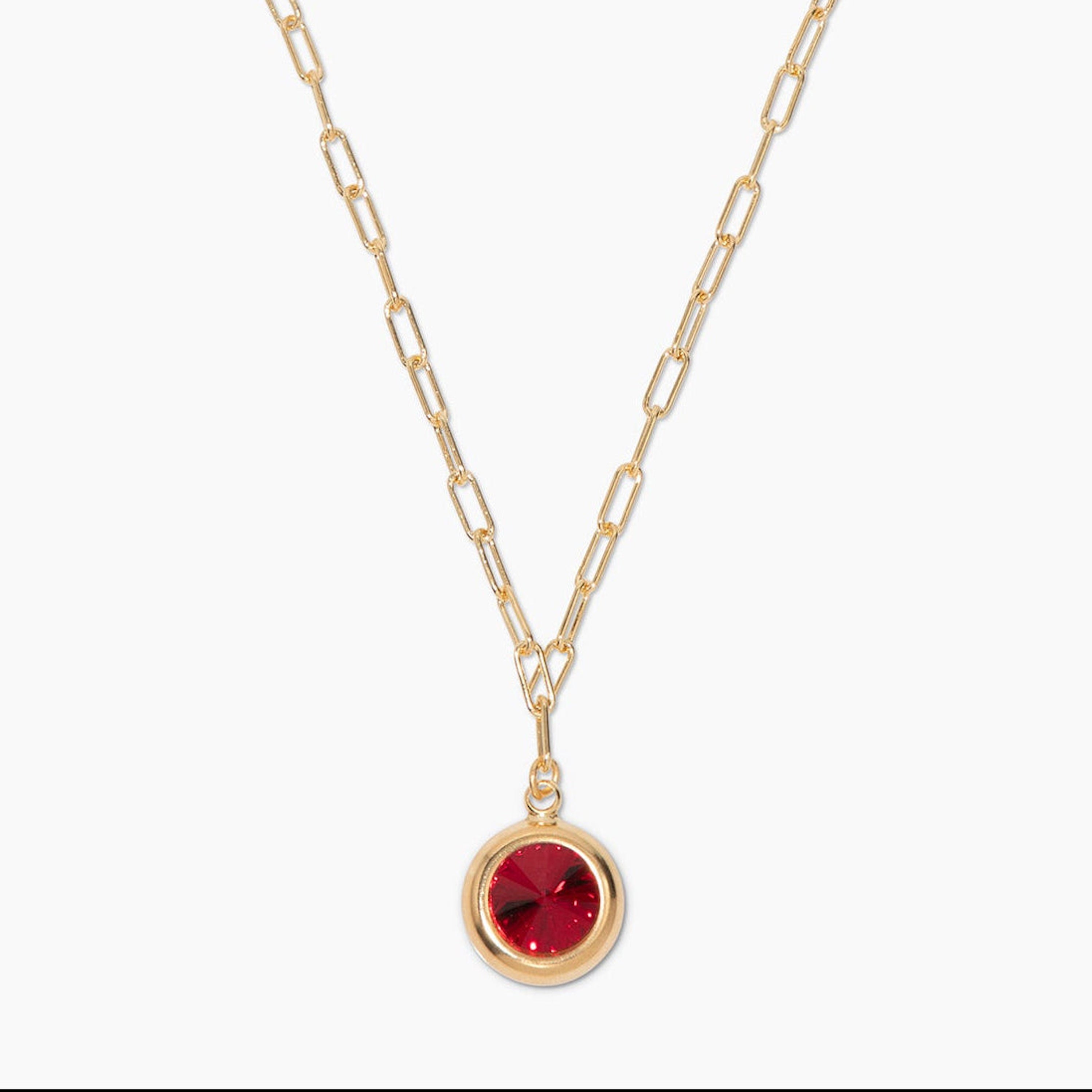 Gold necklace with a red gemstone pendant on a white background