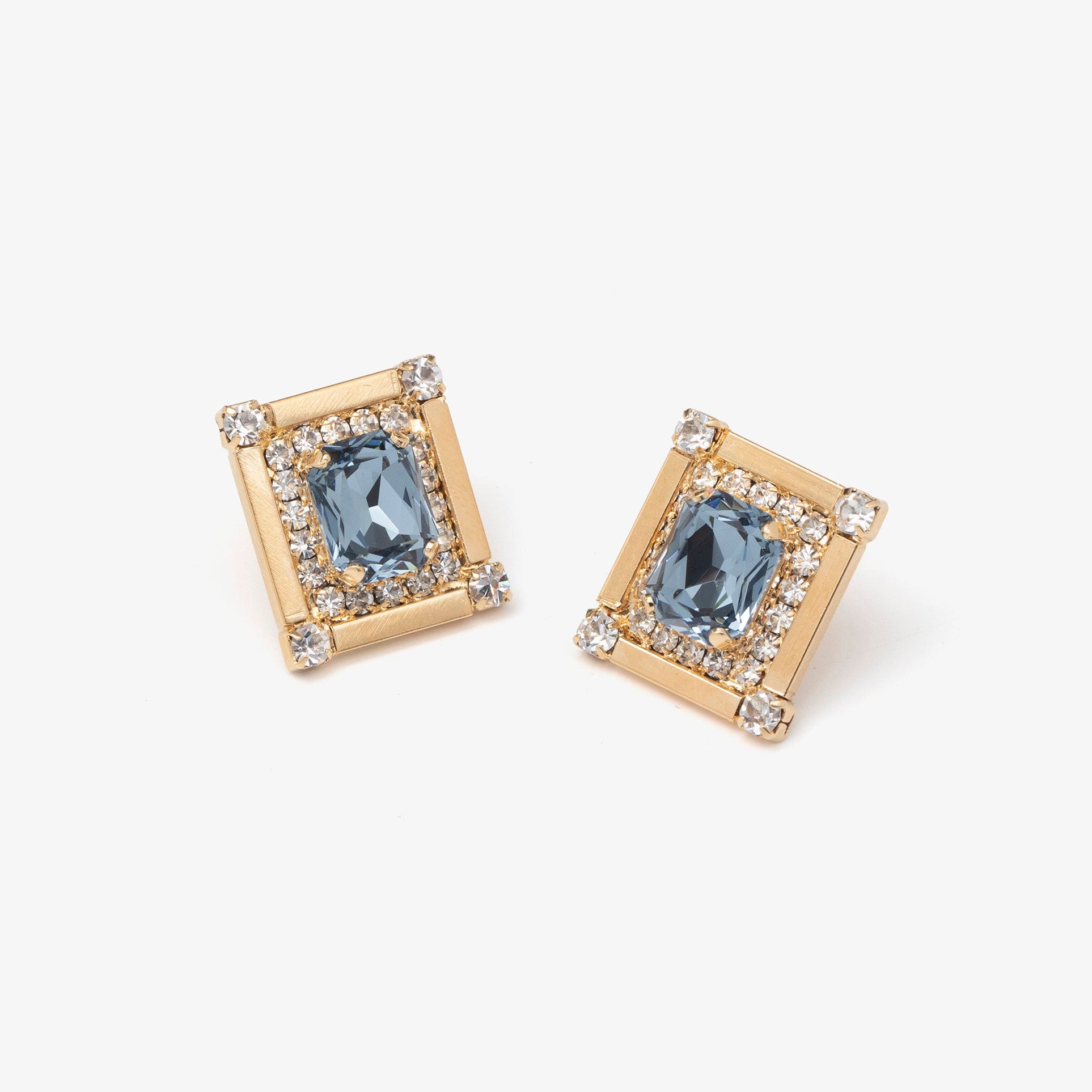 Pair of gold earrings with blue gemstones on a white background