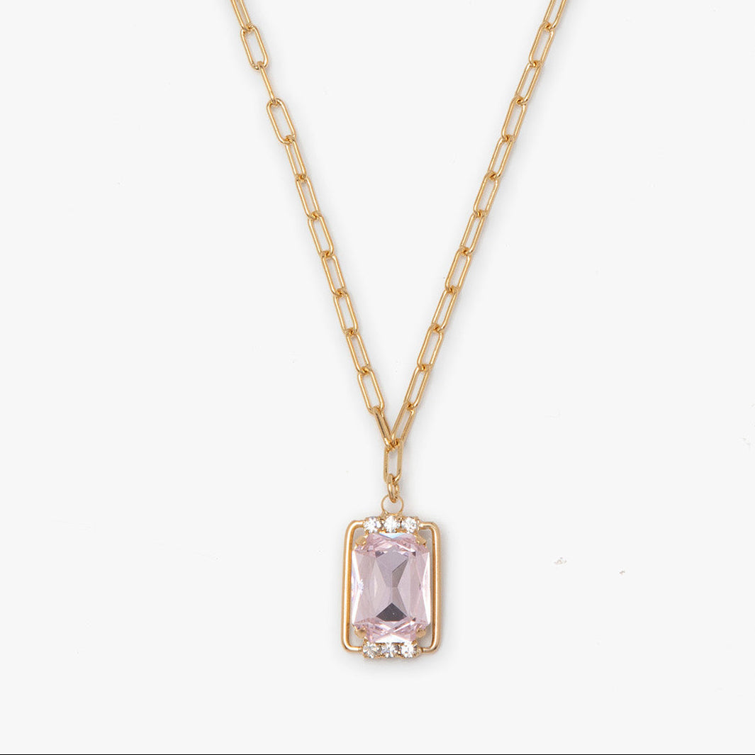 Gold necklace with a pink gemstone pendant on a white background