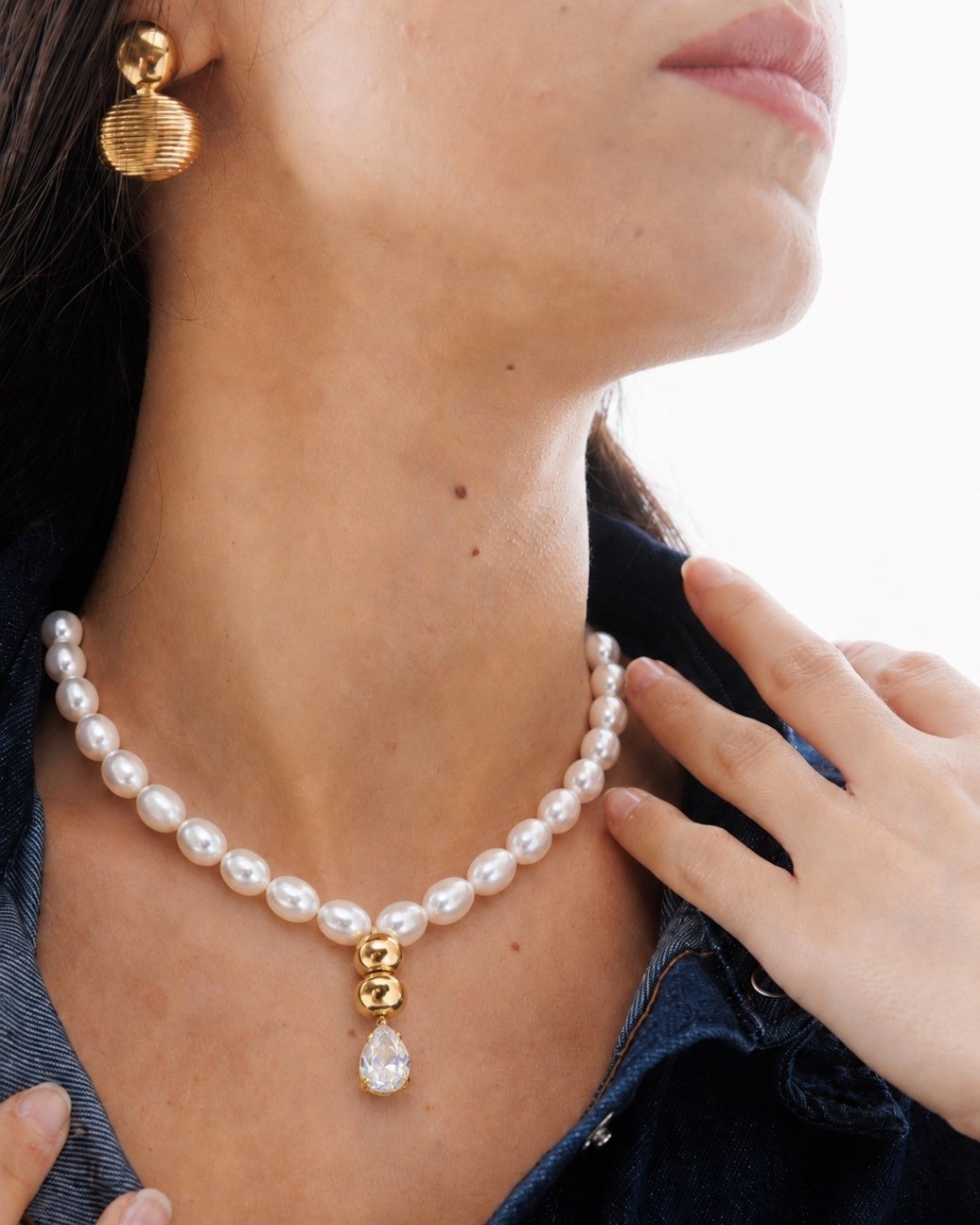 Pearl necklace with a gold clasp worn by a person, with a blurred background.