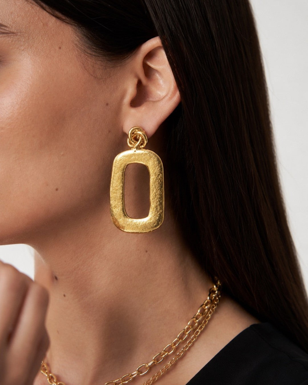 Gold hoop earring worn by a person with a neutral background