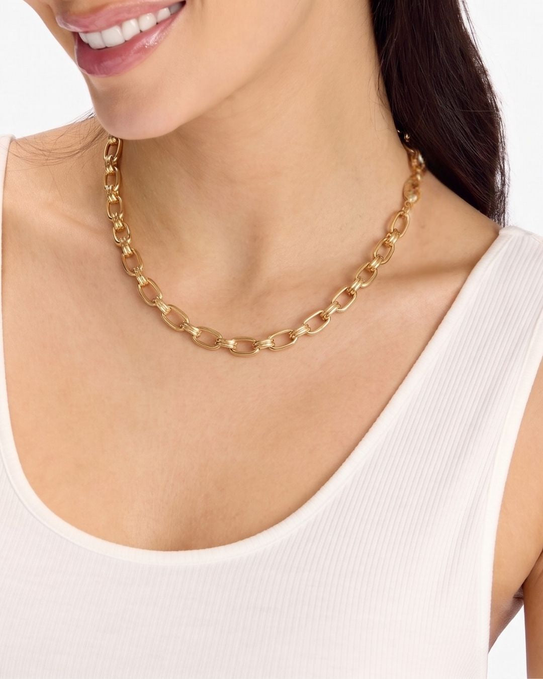 Gold chain necklace worn by a person on a plain background