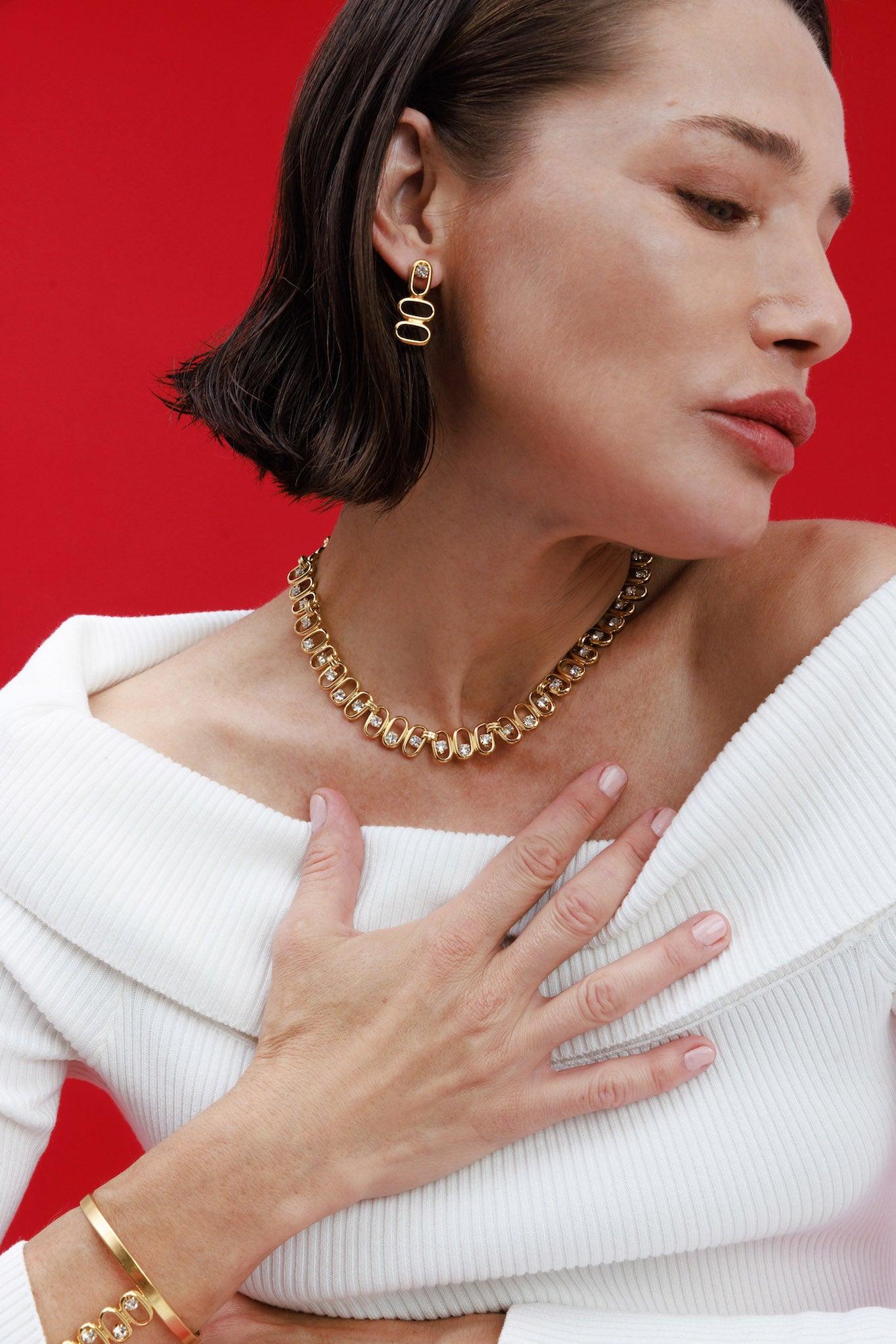 Woman wearing gold jewelry against a red background