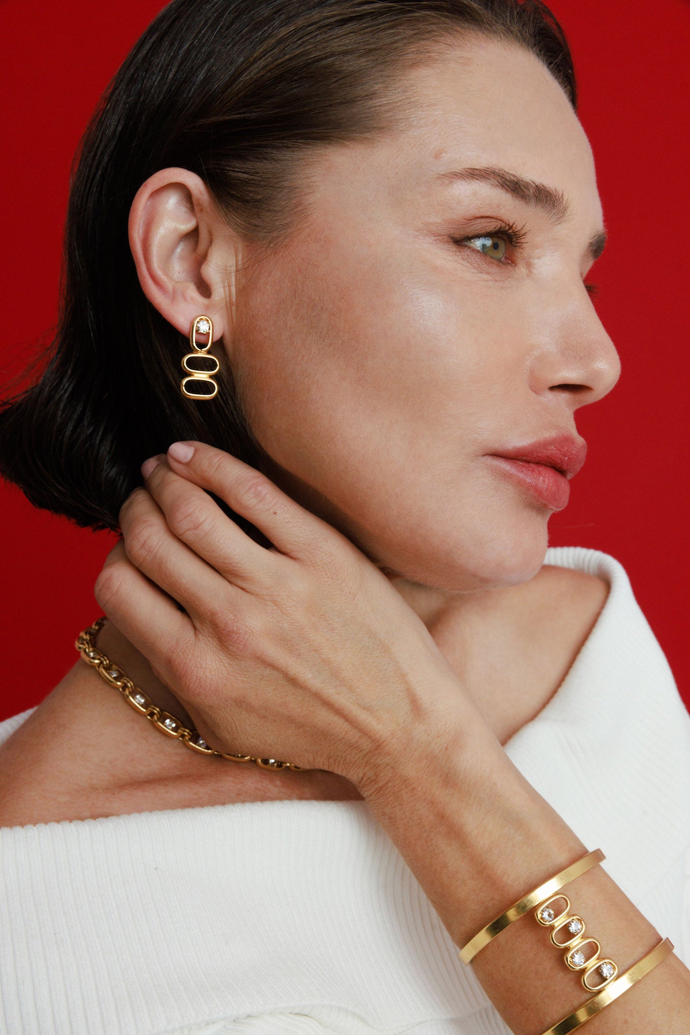 Woman wearing gold jewelry against a red background